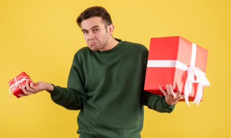 Недовольный мужчина держит 2 подарка