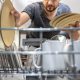 мужчина закладывает в посудомоечную машину тарелки