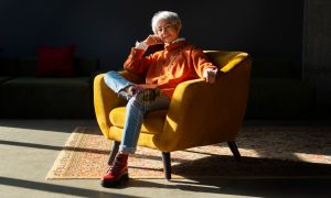 Женщина улыбается, сидя в кресле