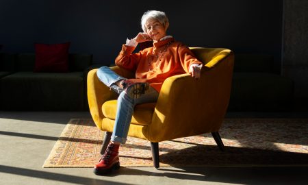 Женщина улыбается, сидя в кресле