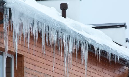 Сосульки свисают с крыши частного дома.