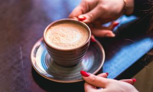 Женщина держит чашку с кофе на тарелке