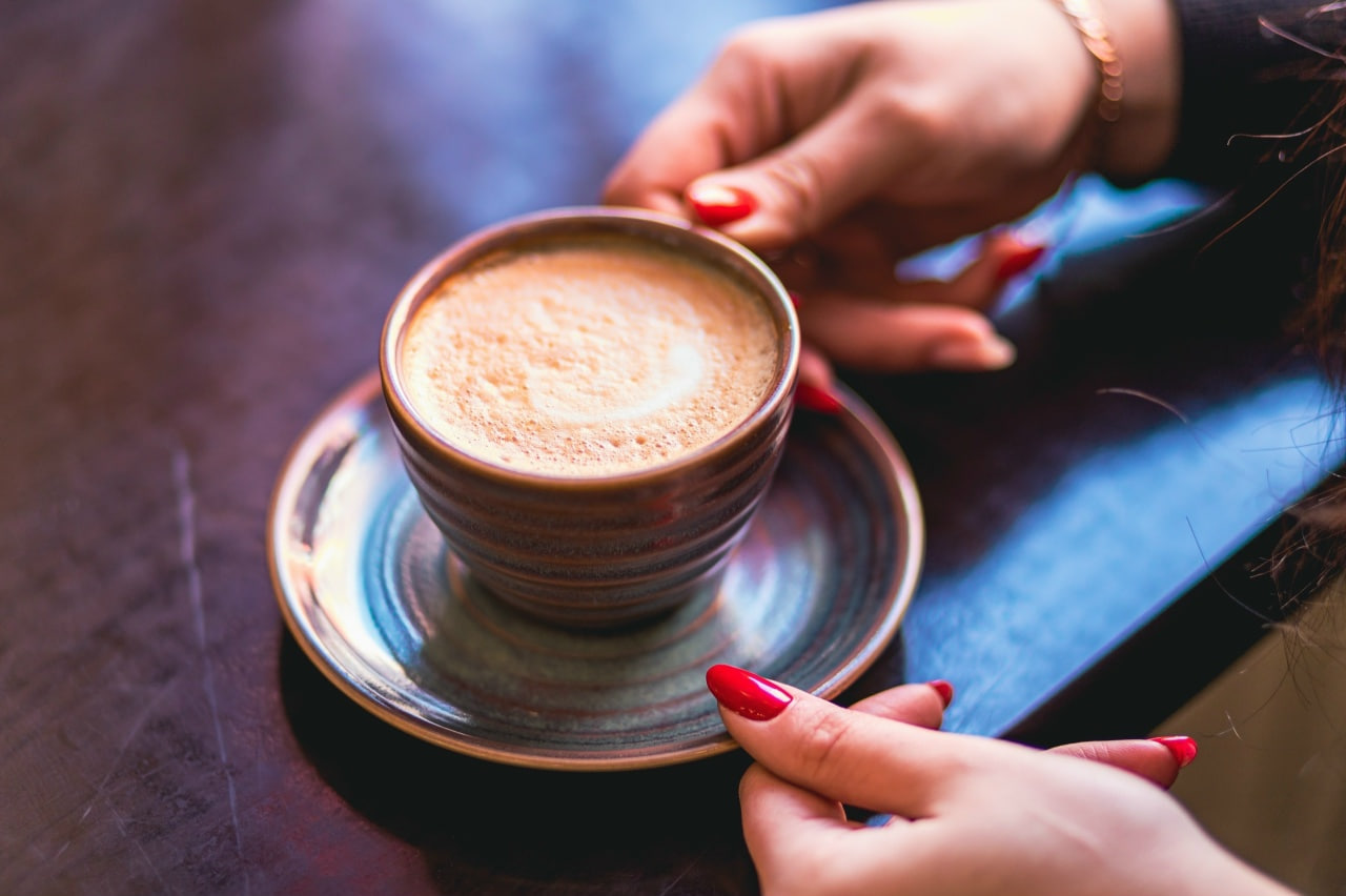 Женщина держит чашку с кофе на тарелке