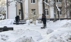 Дворник убирает лопатой снег
