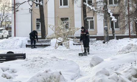 Дворник убирает лопатой снег