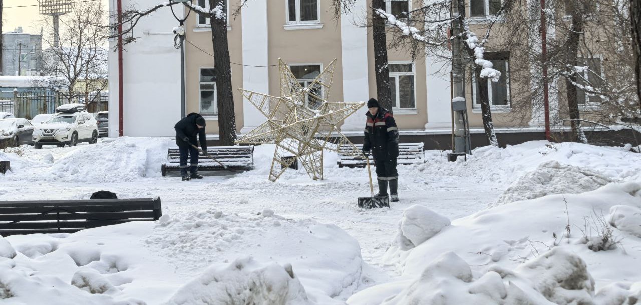 Дворник убирает лопатой снег