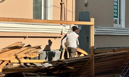 Рабочий ремонтирует здание