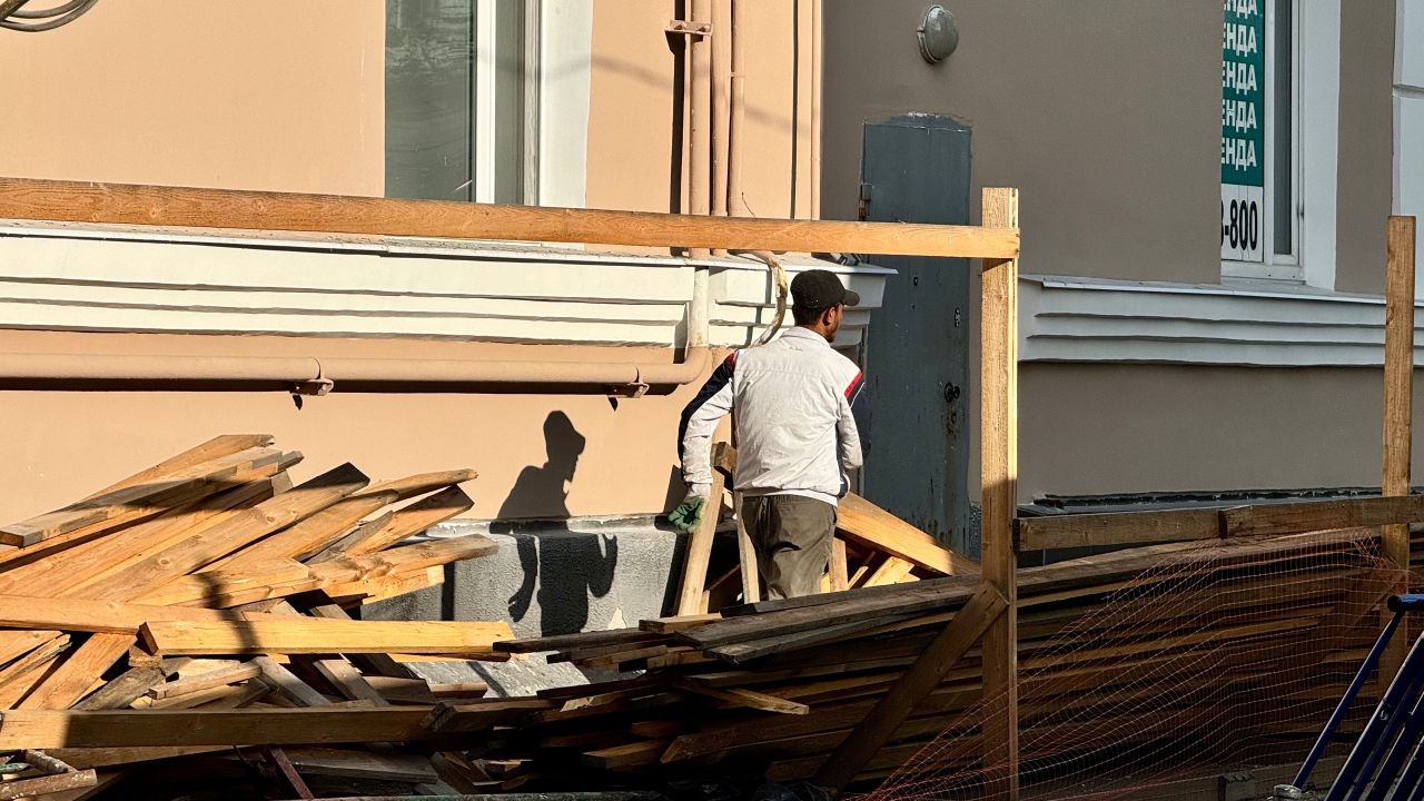 Рабочий ремонтирует здание