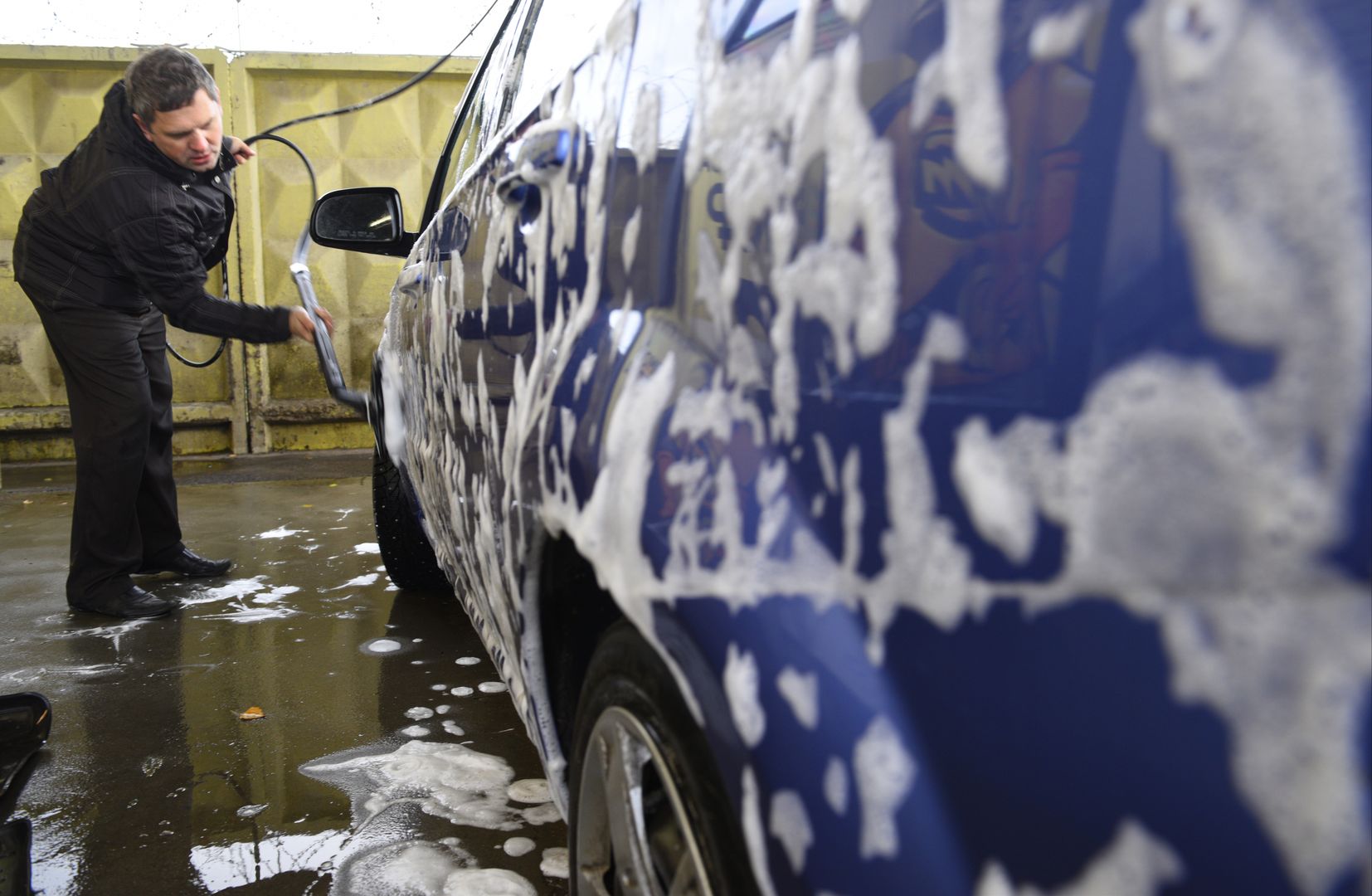 Мужчина моет машину