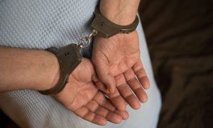 Человек стоит в наручниках