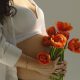 Беременная женщина держит цветы