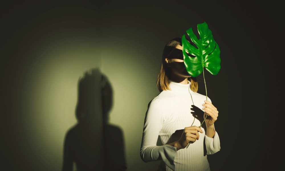 Девушка держит перед лицом лист монстеры