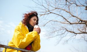 Девушка в желтой куртке со стаканчиком кофе в руках на улице весной