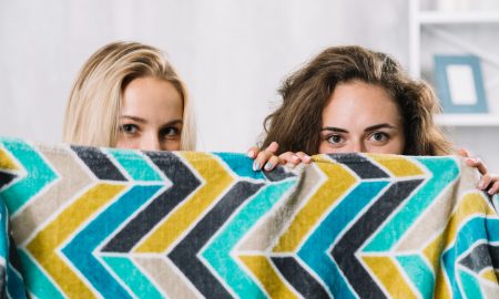 Дае девушки выглядывают из-за пестрого покрывала