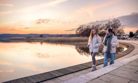 Две девушки гуляют по набережной в парке весной.