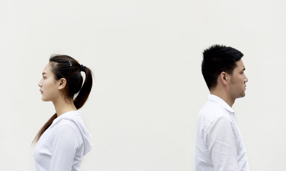 Мужчина и женщина в белой одежде стоят, отвернувшись друг от друга