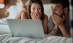 Мужчина и женщина в постели смотрят на экран ноутбука