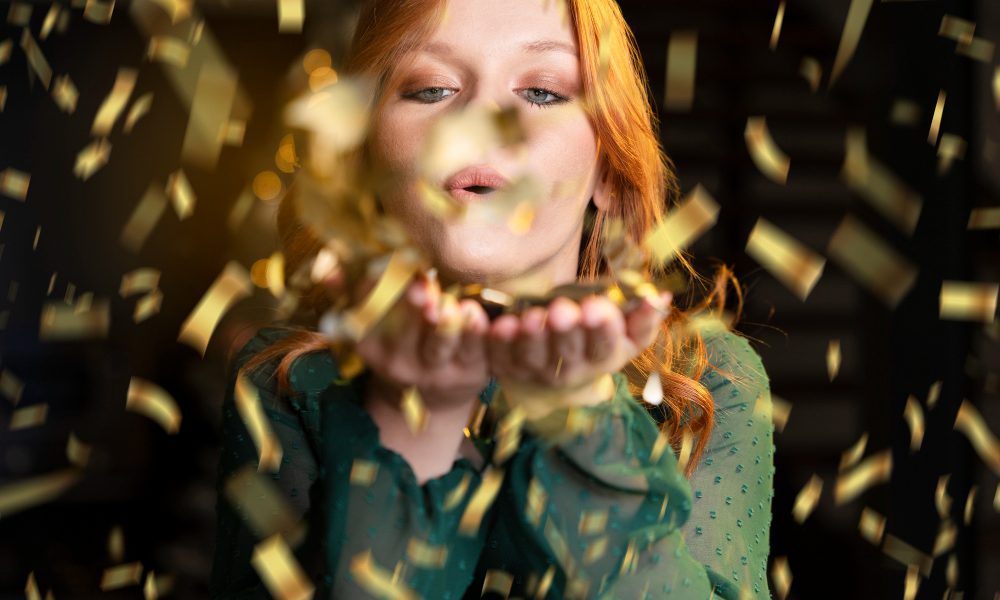 Девушка дует на блестки, которые летят по воздуху.