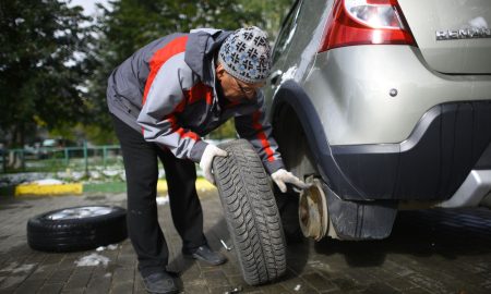 Мужчина меняет колесо авто