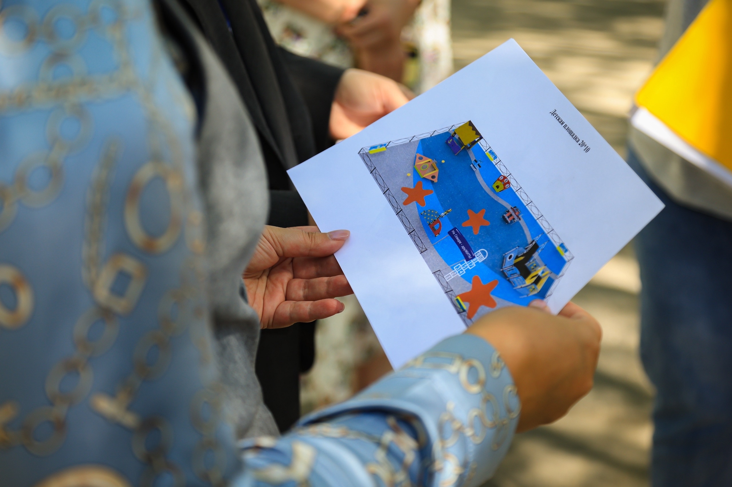 Люди рассматривают проект детской площадки