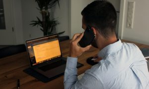 Мужчина говорит по телефону за ноутбуком