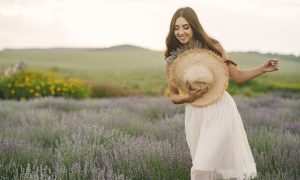 Счастливая девушка идет по цветущему полю.