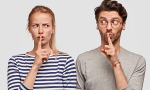 Девушка и молодой человек жестом призывают к молчанию.