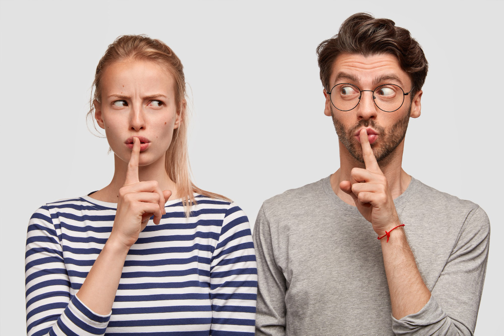 Девушка и молодой человек жестом призывают к молчанию.