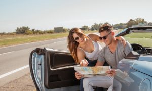 Мужчина и женщина изучают карту, сидя в автомобиле.