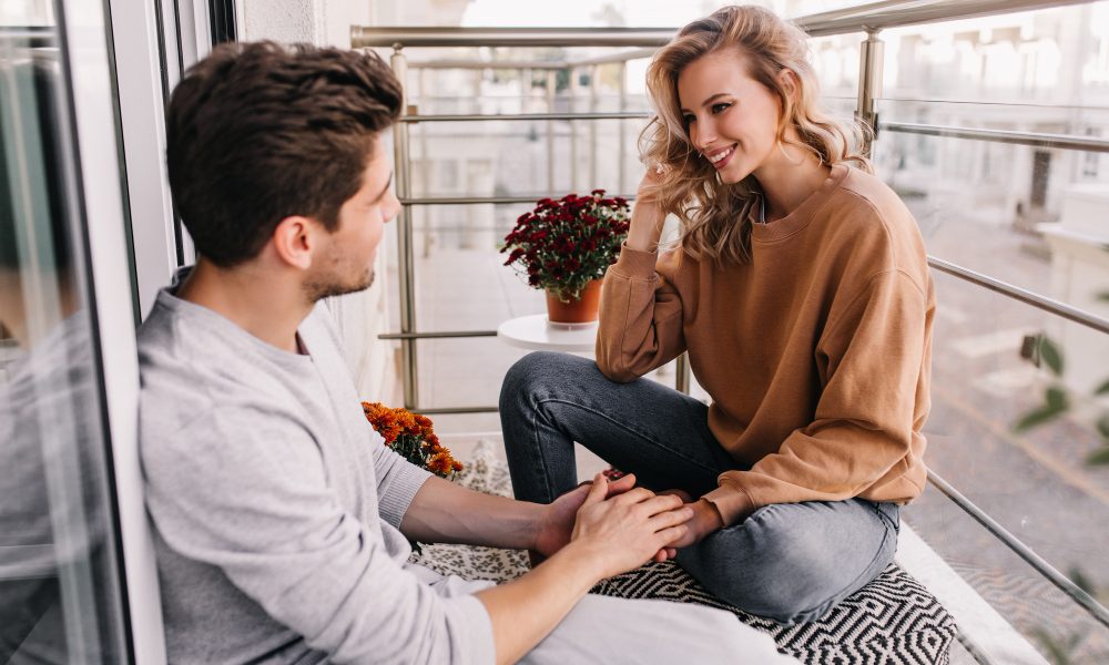 Парень и девушка общаются, сидя на балконе.