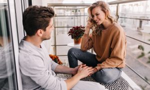 Парень и девушка общаются, сидя на балконе.