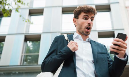 Молодой человек смотрит на экран телефона и пугается.