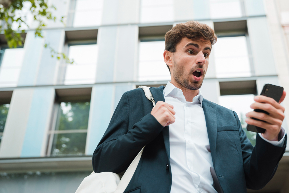 Молодой человек смотрит на экран телефона и пугается.