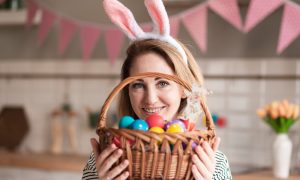 Девушка на Пасху держит в руках корзину с крашеными яйцами.