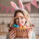 Девушка на Пасху держит в руках корзину с крашеными яйцами.