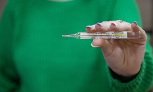 Девушка держит термометр