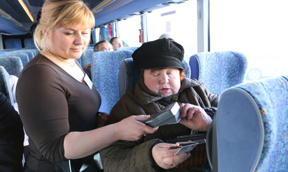 Контролер обилечивает пассажирку в автобусе.
