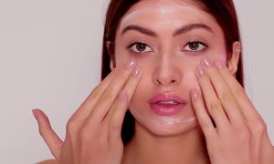 девушка наносит крем на лицо