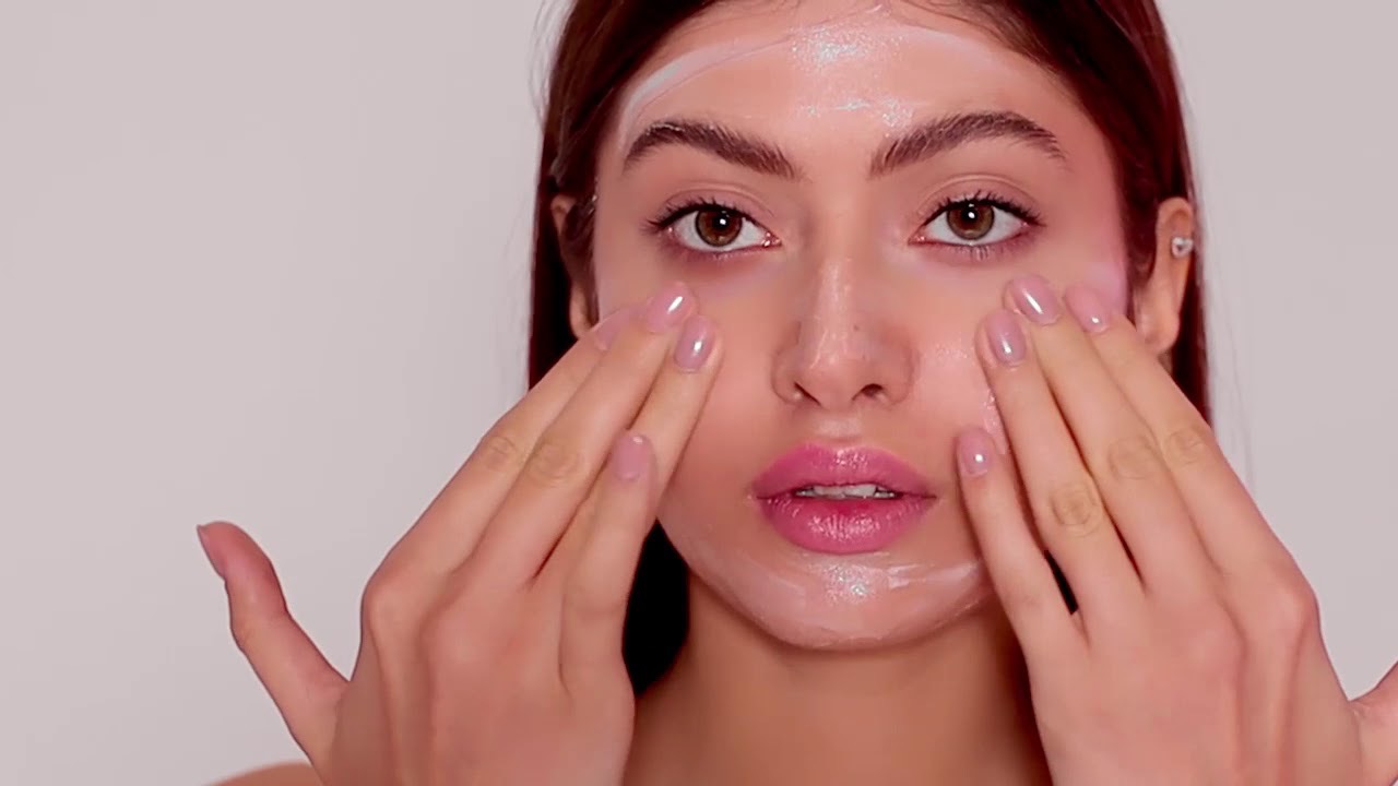 девушка наносит крем на лицо
