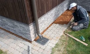 выкладывает плиты у дома