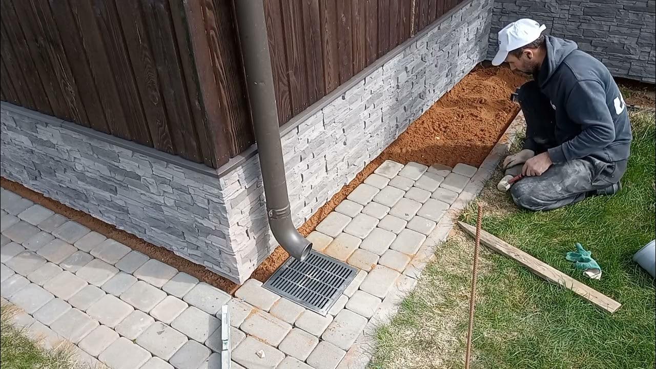 выкладывает плиты у дома