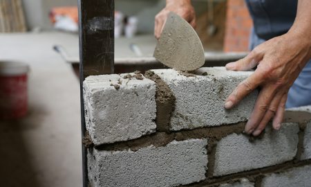 Кладет кирпичи