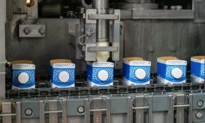 Автоматическая линия розлива молока в сине-белые картонные пакеты на конвейере завода.