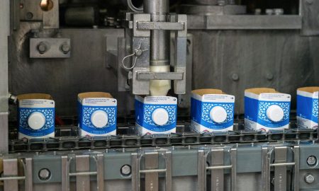 Автоматическая линия розлива молока в сине-белые картонные пакеты на конвейере завода.