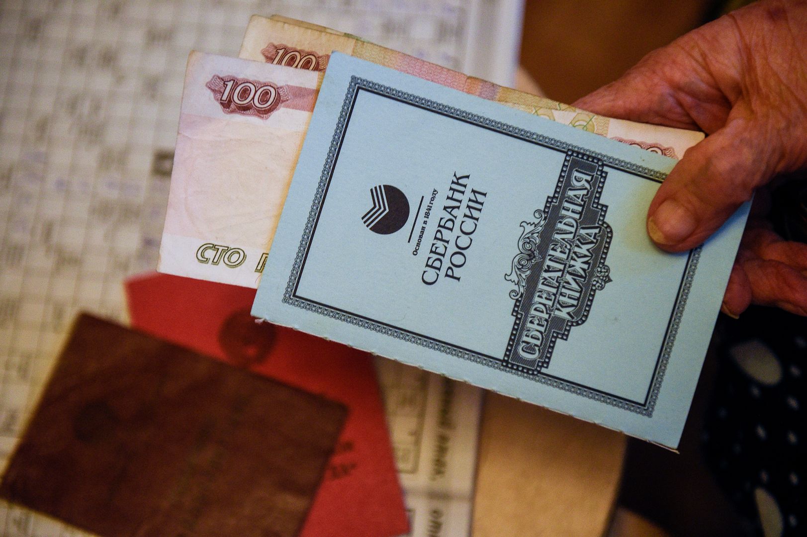 Пенсионерка с пенсионным удостверение, удостверением ветерана труда и сберегательной книжкой сбербанка России.