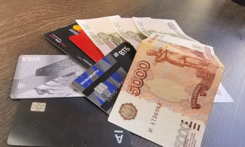 Банковские карты и российские рубли крупным планом на столе.