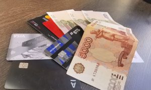 Банковские карты и российские рубли крупным планом на столе.