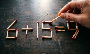Арифметическое уравнение 6+15=9, выложенное из деревянных спичек на тёмной поверхности.
