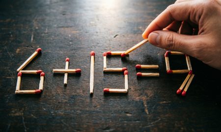 Арифметическое уравнение 6+15=9, выложенное из деревянных спичек на тёмной поверхности.
