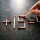 Арифметическое уравнение 6+15=9, выложенное из деревянных спичек на тёмной поверхности.